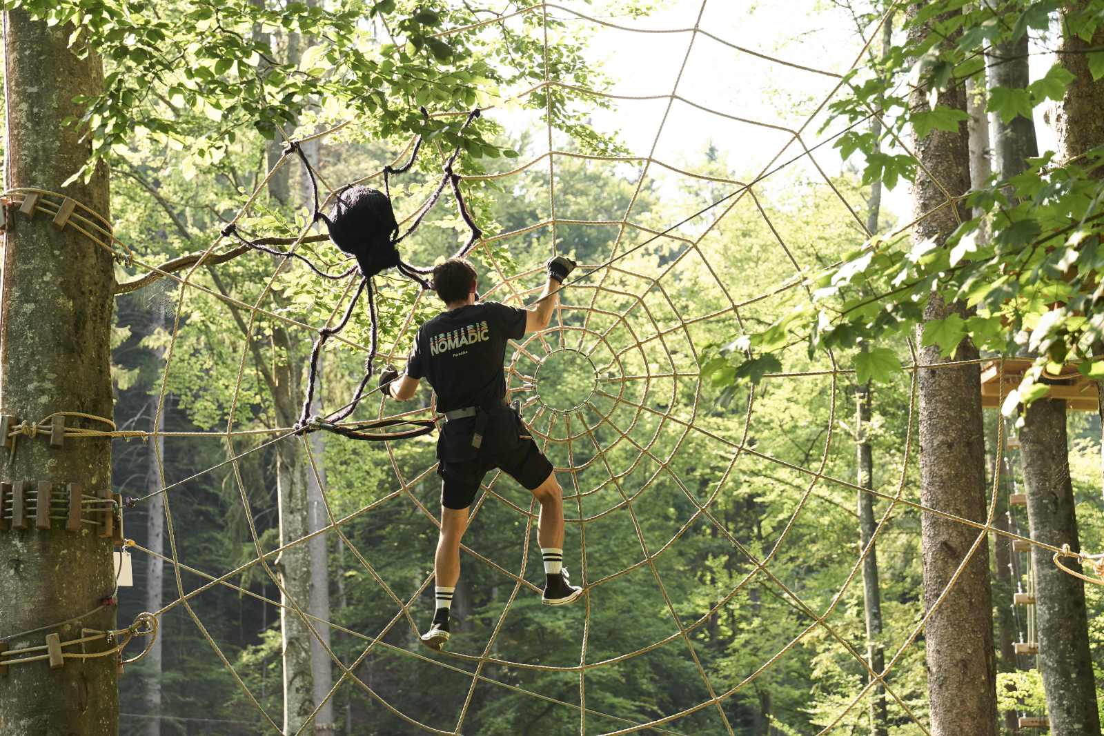 man climbing in spider web made of hemp ropes